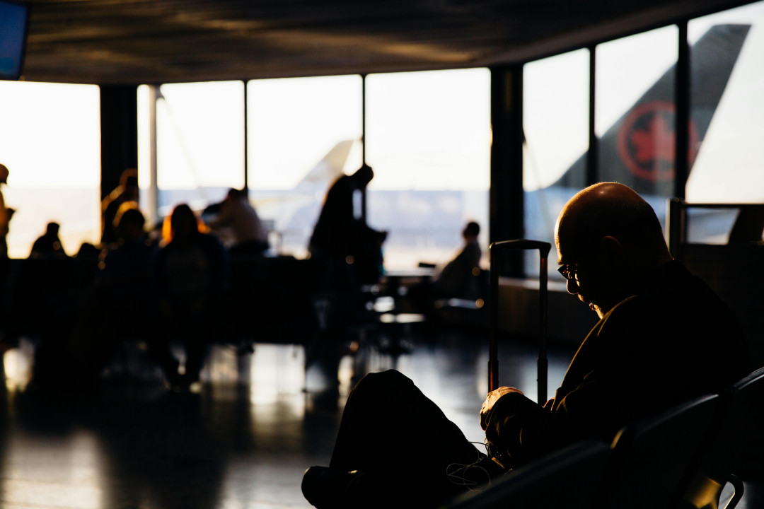 man-sitting-in-airport-terminal-with-luggage-at-sunset-silhouette-image