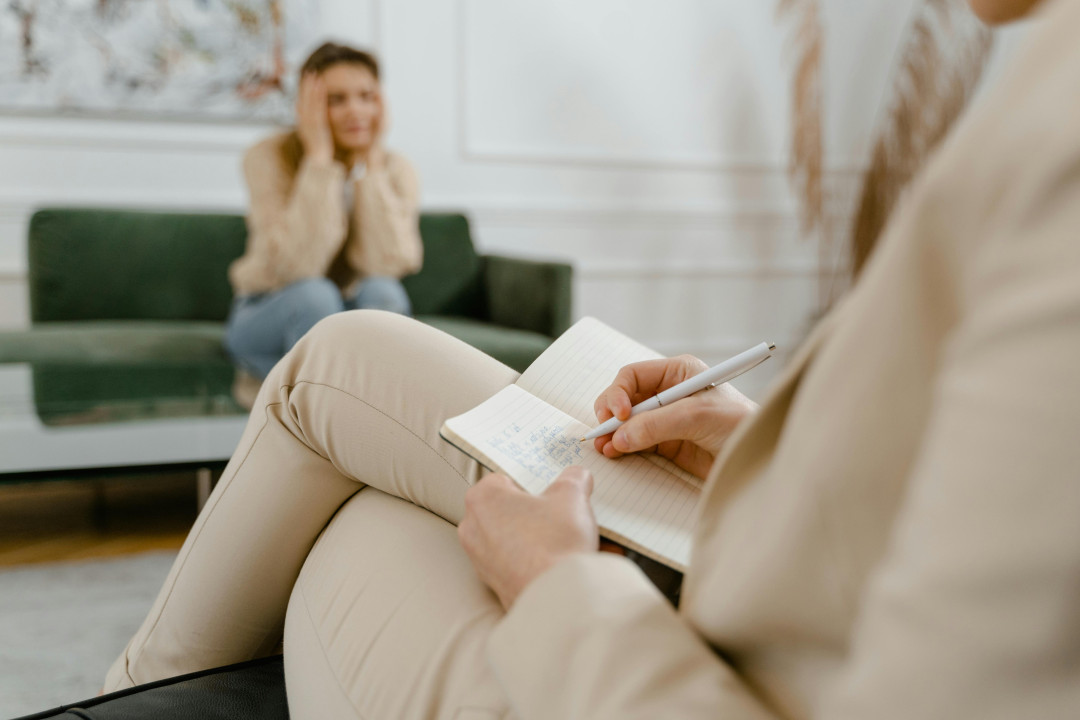 female-psychologist-taking-notes-during-therapy-session-image