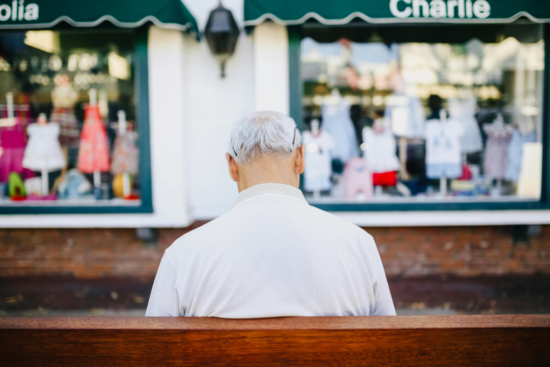 man_in_white_shirt_sitting_on_brown_wooden_bench_outdoors_image