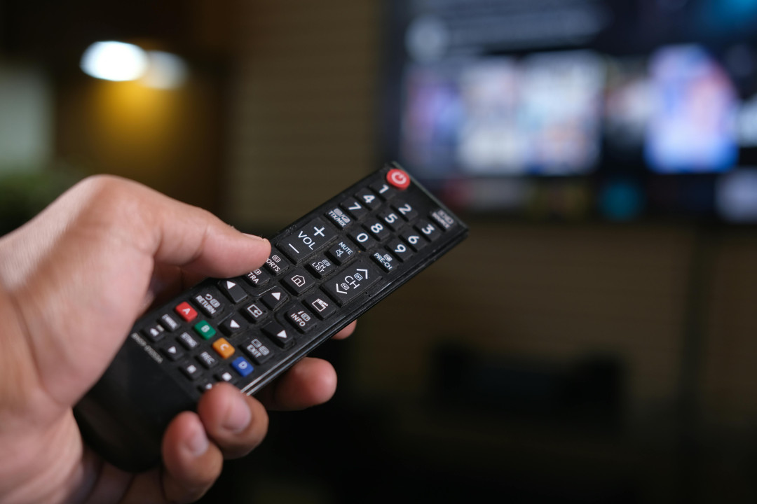 hand-holding-remote-control-in-front-of-tv-image