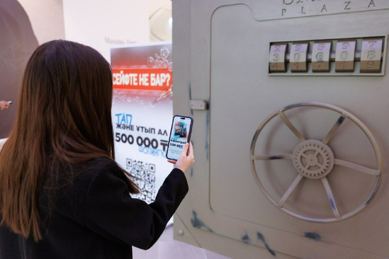 woman-using-smart-plaza-app-in-front-of-mystery-safe-at-dostyk-plaza-image