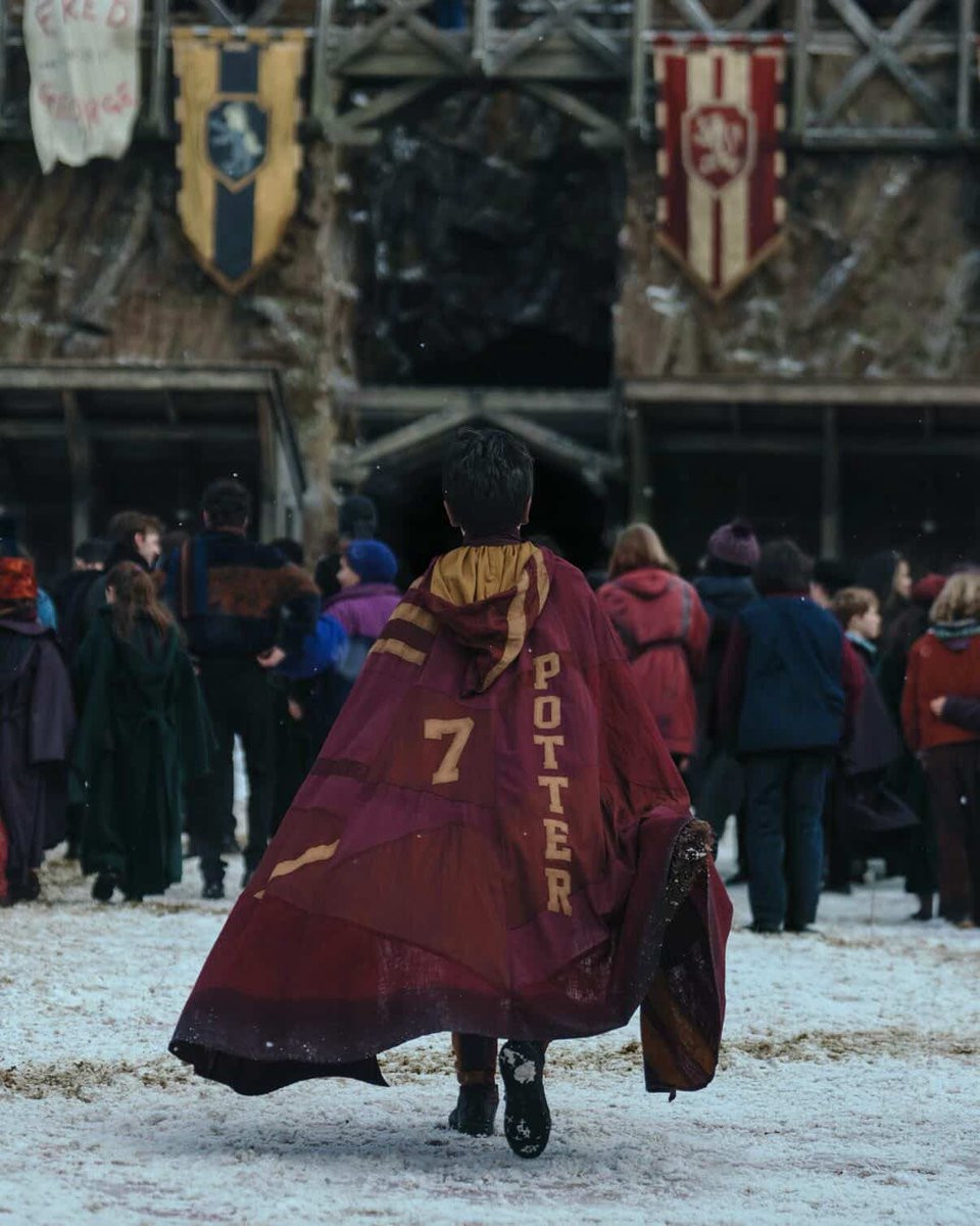 harry-potter-walking-in-snowy-hogwarts-courtyard-with-broom-and-gryffindor-robe-image