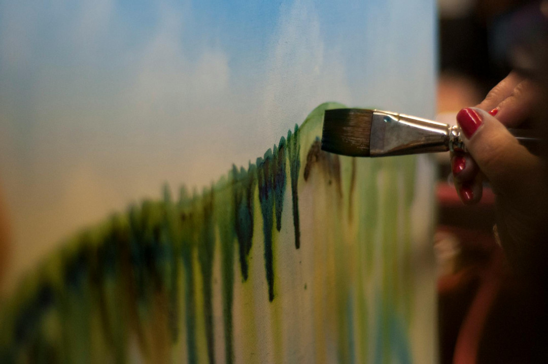 hand-holding-paintbrush-painting-on-canvas-image
